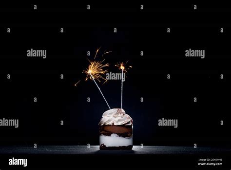 Delicious Birthday Cupcake With Firework Candle On Table Against Dark