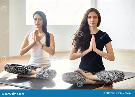 Two Young Women Meditating In Lotus Pose With Hands In Namaste Stock