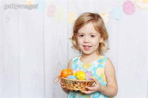 Portrait Of Happy Blonde Girl Holding Colorful Easter Egg In Basket