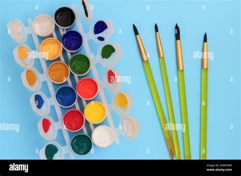 Colorful Paints In Jars On A Blue Background Near The Brushes Color