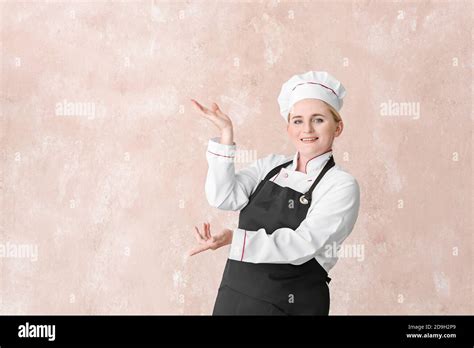 Mature Female Chef Showing Something On Color Background Stock Photo