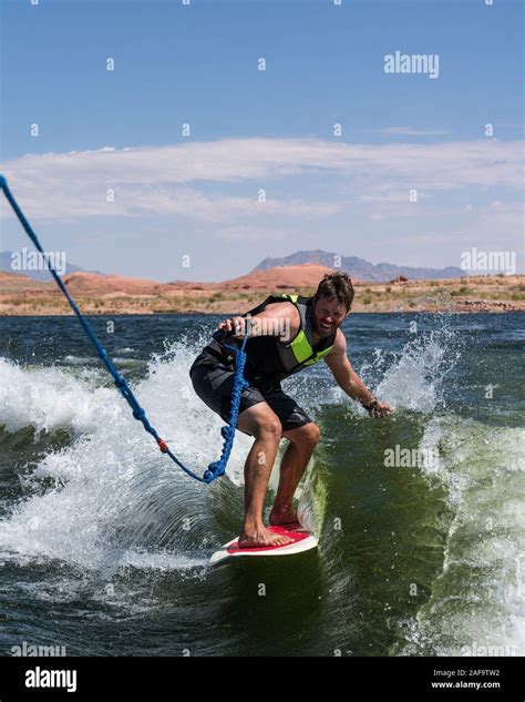 A Young Man Wake Surfing Behind A Boat On Lake Powell In The Glen