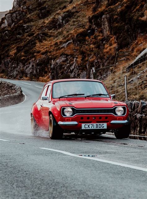 An Old Red Car Driving Down The Road