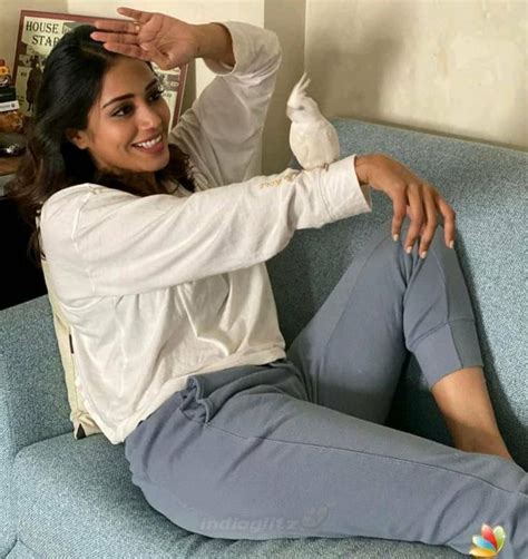 A Woman Sitting On Top Of A Blue Couch Next To A White Bird In Her Hand