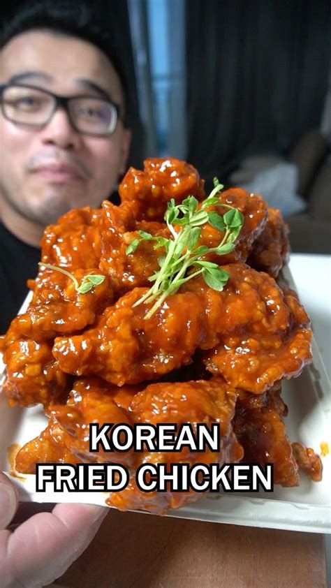 A Man Holding Up A Plate Full Of Chicken Wings With The Words Korean