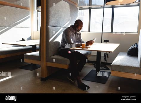 African American Mature Businessman Using Mobile Phone While Having