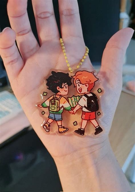 A Hand Holding A Small Plastic Keychain With Two Cartoon Characters On