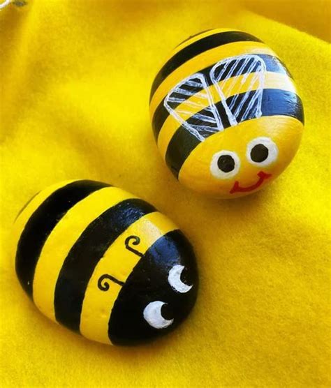 Two Painted Rocks Sitting On Top Of A Yellow Cloth Covered In Black And