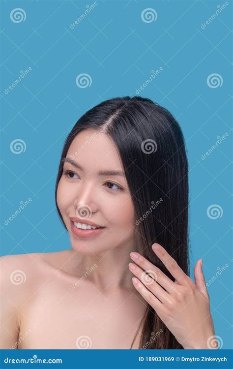 Beautiful And Smiling Long Haired Woman Touching Her Hair Stock Image