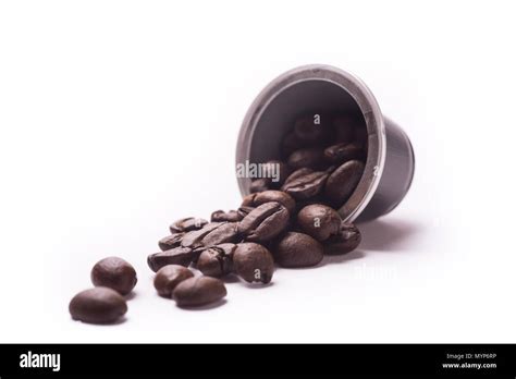 Toasted Coffee Beans Spill Out From A Capsule On White Background Stock