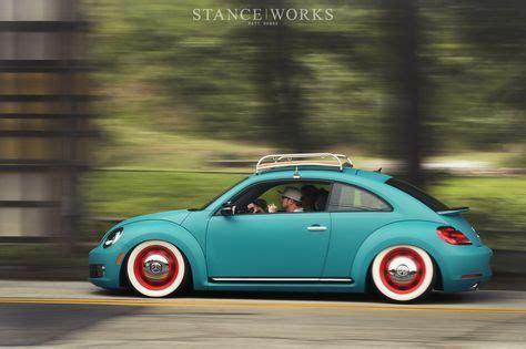 A Blue Car With Red Rims Driving Down The Road