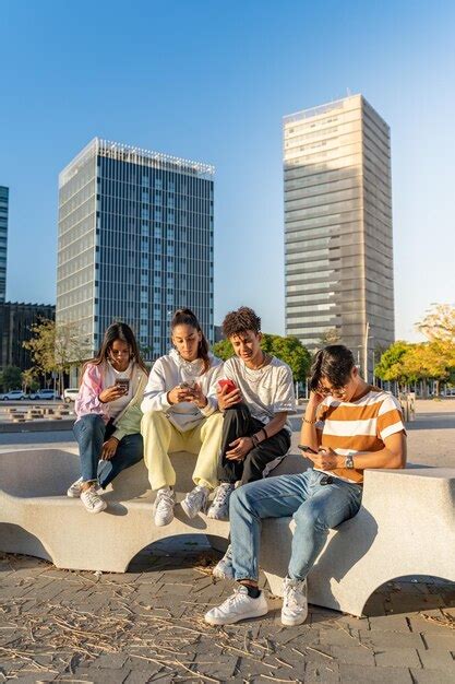 Grupo De Amigos Adolescentes Felizes Olhando Os Telefones Em Um Banco