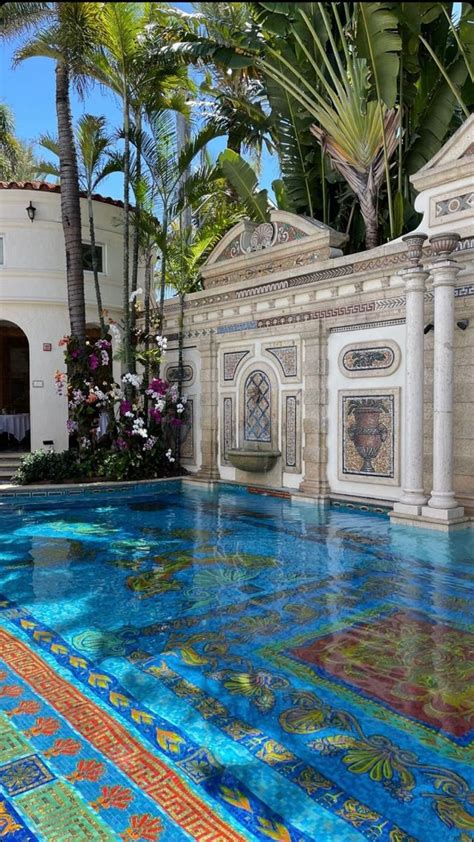 An Outdoor Swimming Pool Surrounded By Palm Trees And Colorful Tile