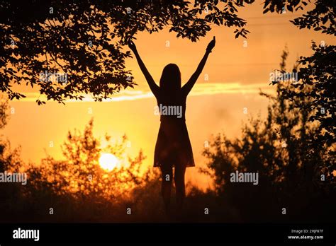 Dark Silhouette Of Young Woman Walking Alone Through Dark Forest