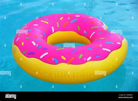 A Pink Plastic Pool Float Shaped Like A Donut With Sprinkles Stock