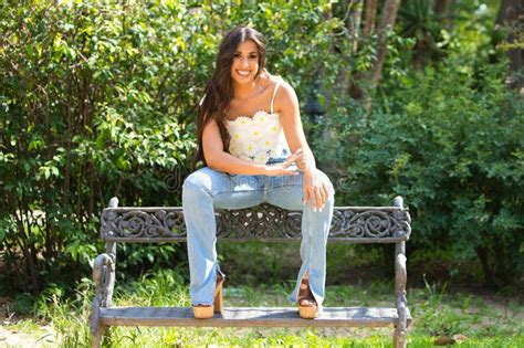 Beautiful Spanish Brunette Woman With Long Curly Hair Sitting On The Bench The Woman Is Happy