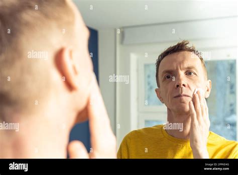 Mature Man Apply Face Tonic With Cotton Pad Then Massage With Hands Male Portrait In Mirror