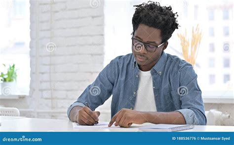 Young African Man Writing On Document In Office Stock Photo Image Of