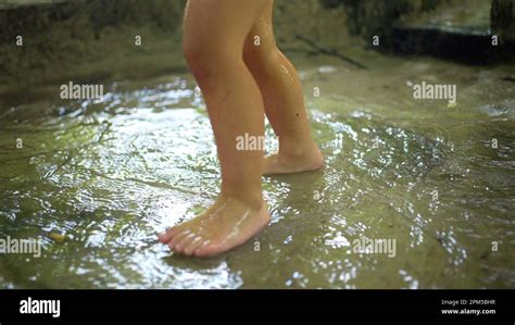 Happy kid jumping into water puddle barefoot during sunny day. Active ...