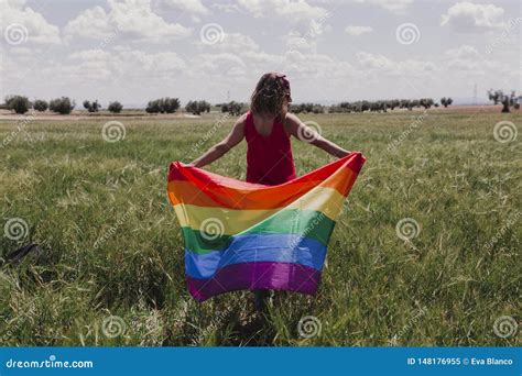 Woman Holding The Gay Rainbow Flag On A Green Meadow Outdoors