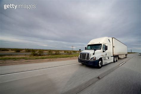 Long Haul Semi Truck Speeding Down A Four Lane Highway To Delivery