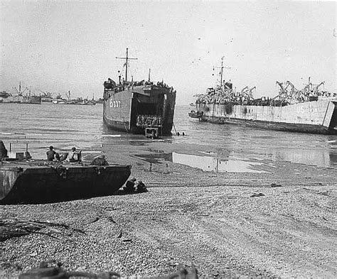 Two Large Ships In The Water Next To Each Other On Land With People