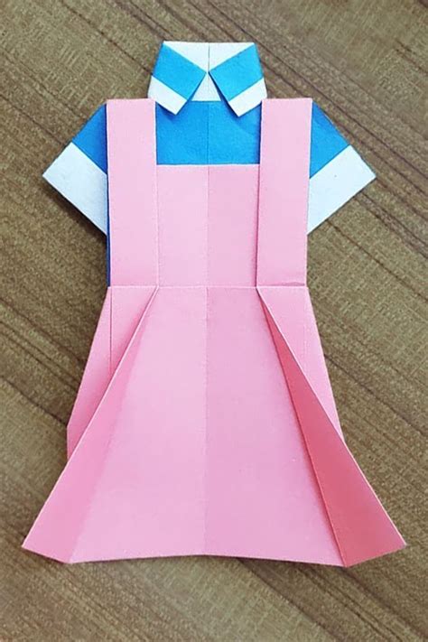 An Origami Dress Made Out Of Paper Sitting On Top Of A Wooden Table