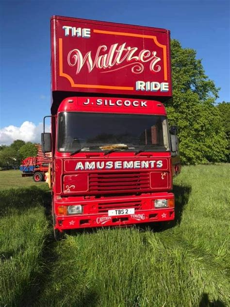 A Large Red Truck Parked On Top Of A Lush Green Field