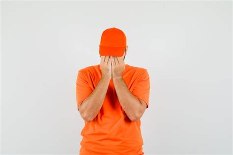 Free Photo Delivery Man Standing With Hands On Waist In Orange T