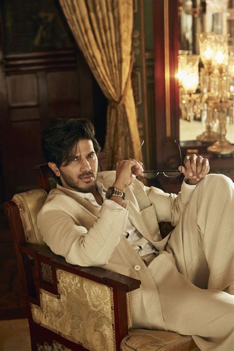 A Man In A Suit Sitting On A Chair Holding A Pair Of Scissors To His Face