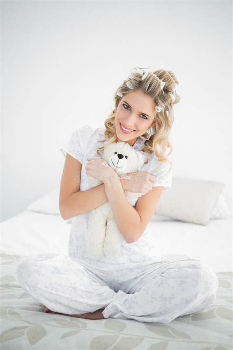 Cheerful Pretty Blonde Wearing Hair Curlers Holding Teddy Bear Stock