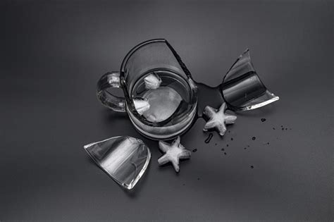 Broken Glass Cup With Water And Ice On A Black Background Stock Photo