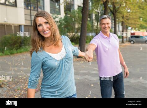 Happy Mature Man Pulling Woman In The Street Stock Photo Alamy
