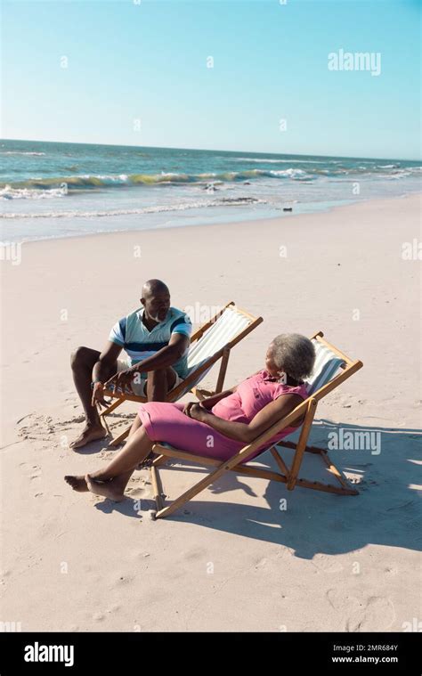 African American Senior Couple Sitting On Deckchairs And Talking At