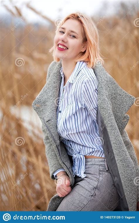 Het Jonge Mooie Blonde In Losgeknoopte Laag Lacht Ongunstig I Riet I De Winter Stock Foto