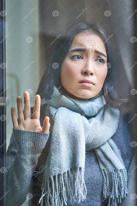 Vertical Shot Of Upset Asian Woman Looking Outside Touching Window