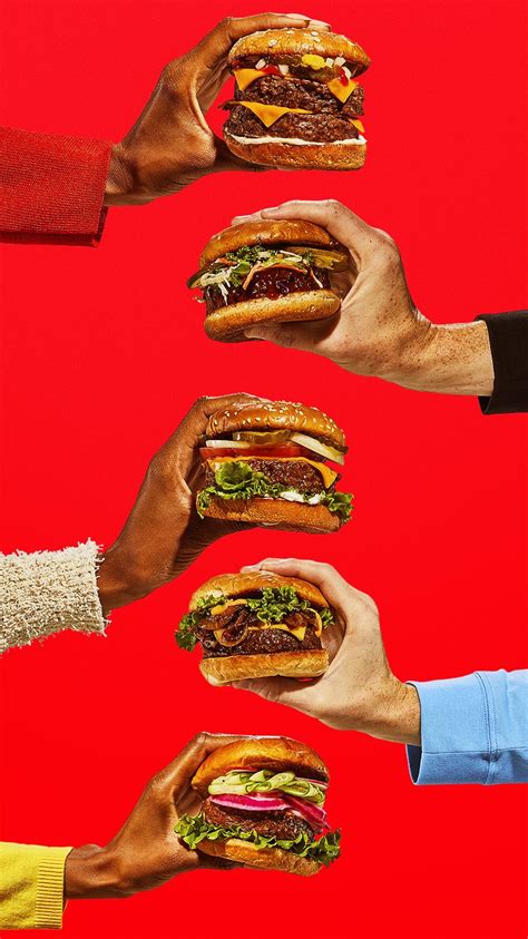 Several Hands Holding Sandwiches In Front Of A Red Background