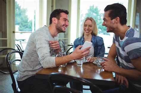 Amigos Que Se Sientan A La Mesa Y Usar El Tel Fono M Vil En Cafeter A