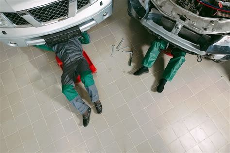 Premium Photo Mechanics In Uniform Lying Down And Working Under Car