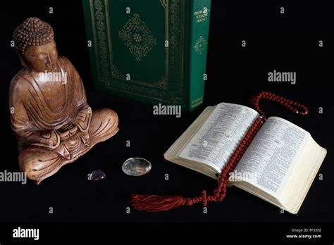 Wooden Statue Of Buddha With Koran And Holy Bible Stock Photo Alamy