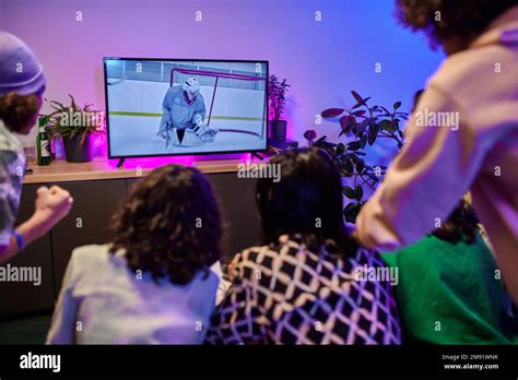 Group Of Tense Youthful Guys And Girls Watching Hockey Match Broadcast