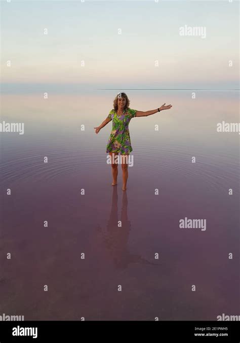 Happy Woman In Bright Dress In The Middle Of Pink Lake Water Is