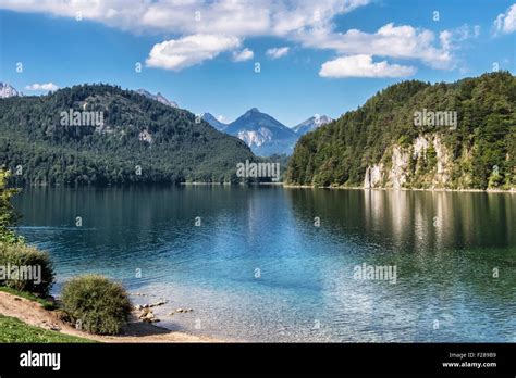 Bavarian landscape view, clear water of Alpsee lake, mountains and blue ...