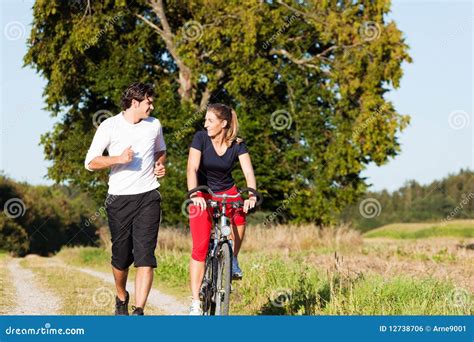 Young Sport Couple Jogging And Cycling Stock Photo Image Of Meadow