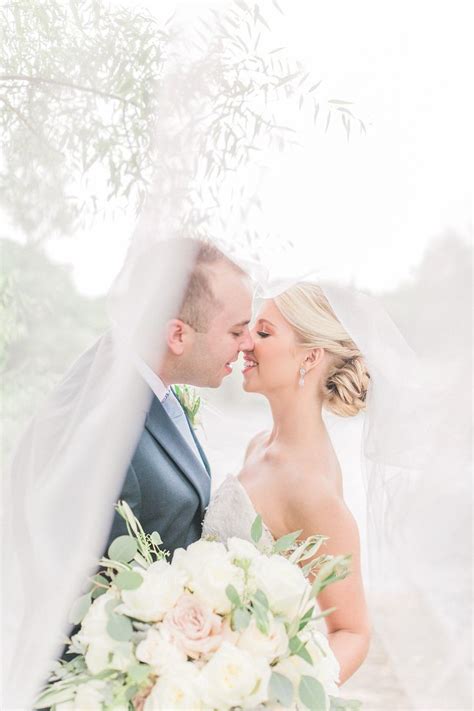 A Bride And Groom Kissing Under A Veil