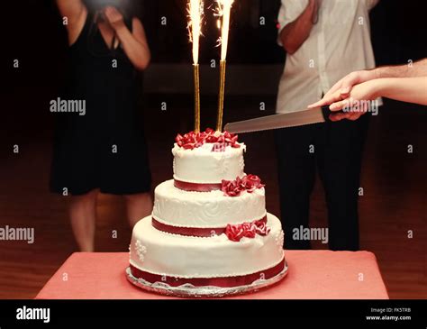 Close Up Of Bride And Groom Cutting Wedding Cake Fireworks Stock Photo