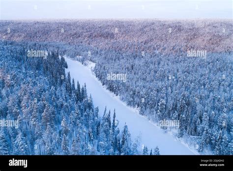 Snow And Ice Covered River Valley Surrounded With A Wintery Taiga