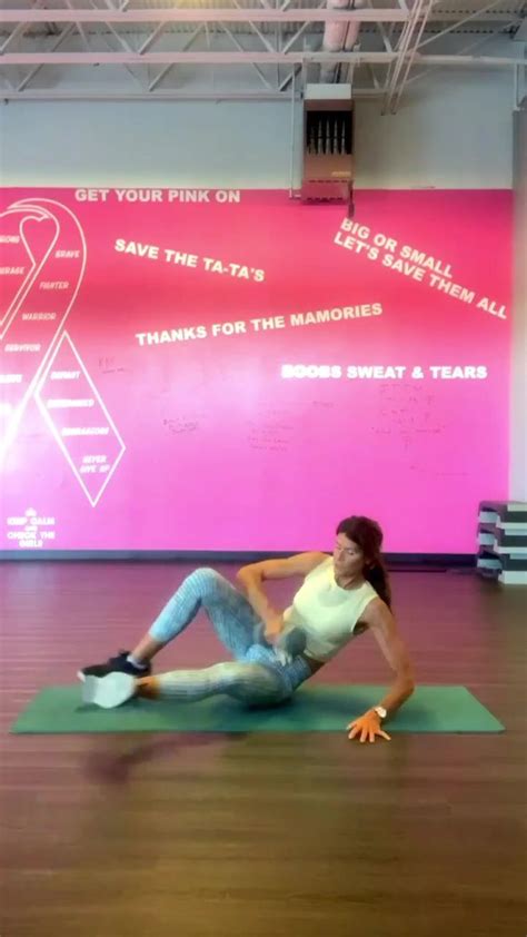 A Woman Sitting On Top Of A Green Mat In A Room With Pink Wall Behind Her