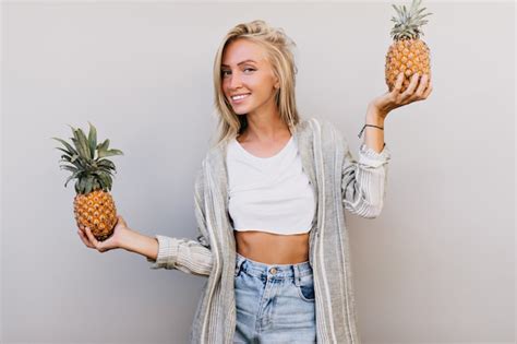 Belle femme à la mode avec des ananas souriant à la caméra femme blonde en tenue décontractée