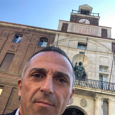 A Man Standing In Front Of A Building With A Clock On It S Tower